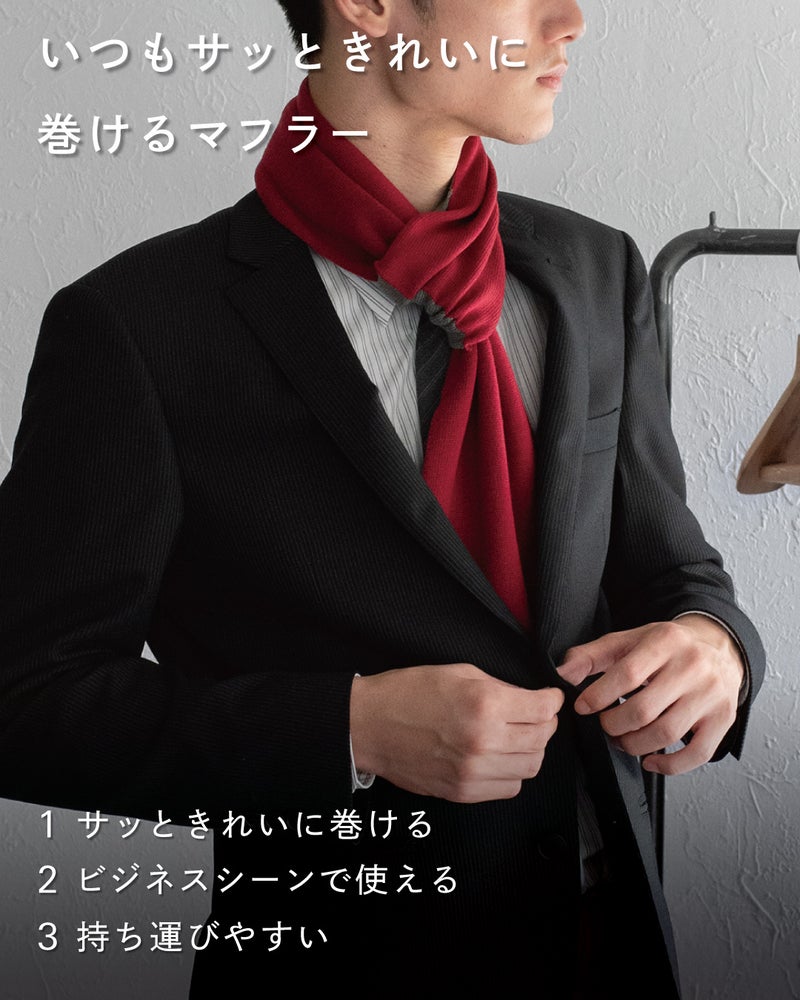 赤いミニマフラーを着用したビジネスマン。スーツ姿にマフラーが映え、手軽に巻けてビジネスシーンにも使えることを表現。