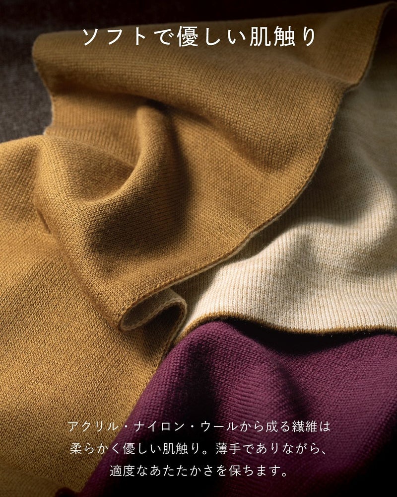 柔らかい肌触りを表現するマフラーのクローズアップ。イエローオーカー、オフホワイト、ワインレッドのマフラーが重ねられている。