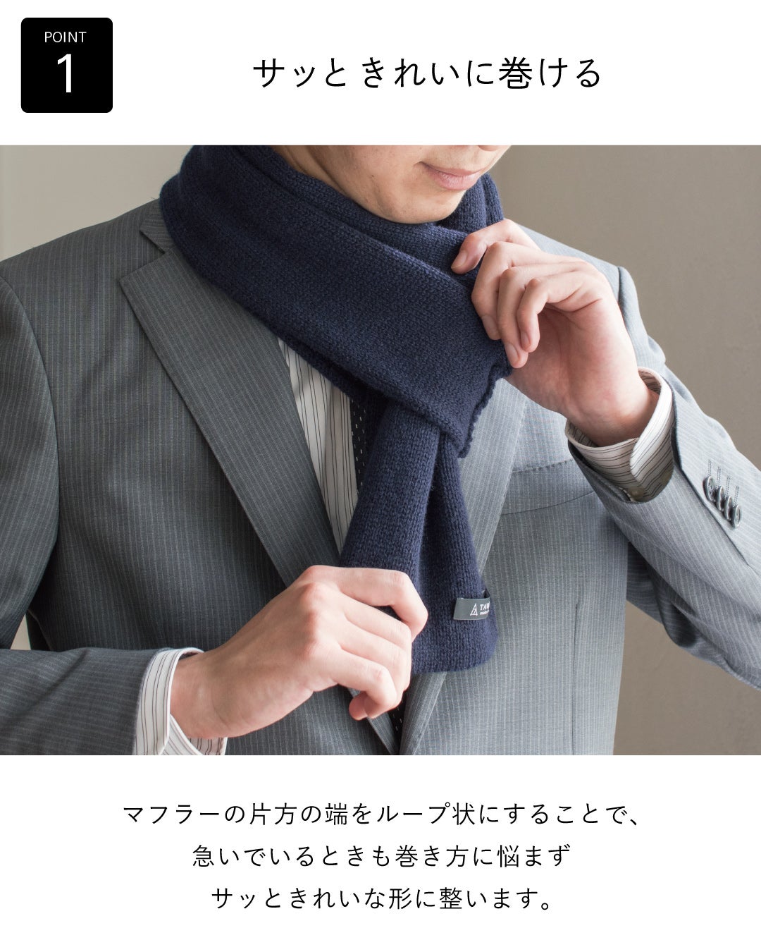 グレーのスーツにネイビーのカシミヤ3秒マフラーを巻き、片端のループに通すだけで急いでいる朝もサッときれいな形に整う使いやすさを伝える画像。