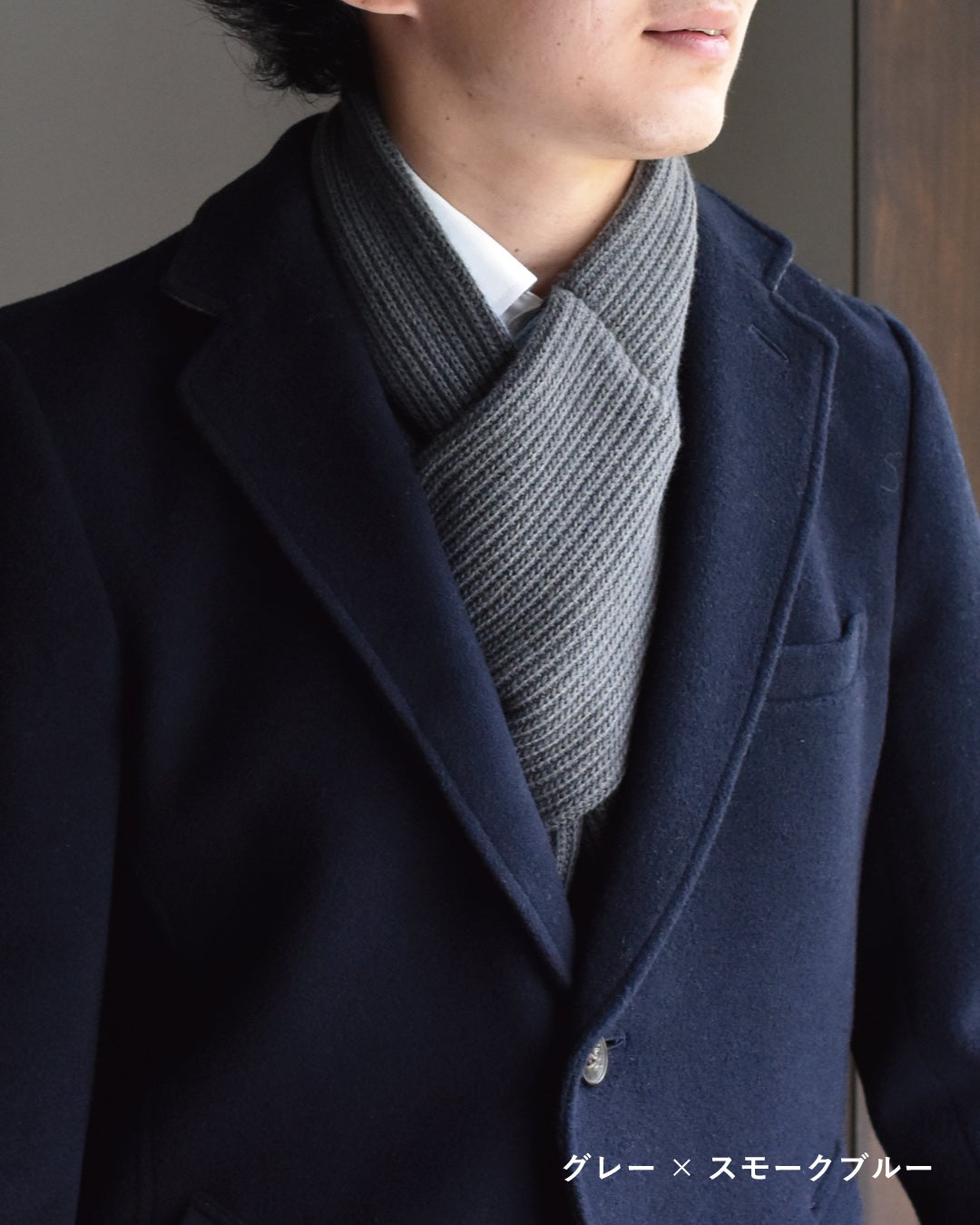 ネイビーのウールコートの首元にグレー×スモークブルーの3秒マフラー リブ編みを合わせ、端正なグレーがビジネスの装いに馴染む着用カット。
