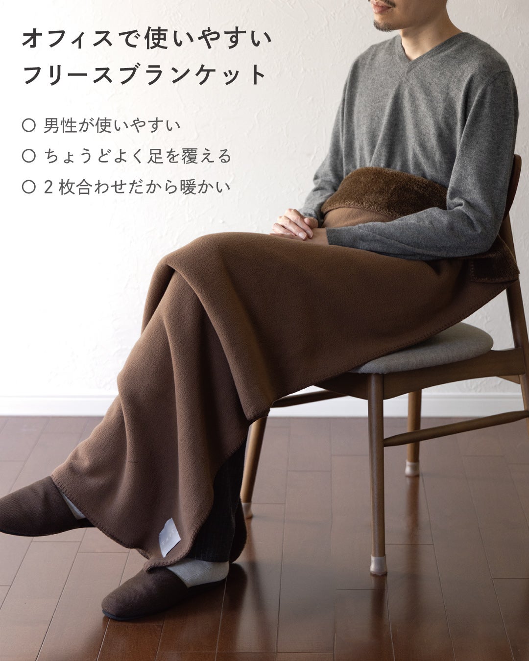 オフィスで使いやすいMr. ブランケットのブラウンをひざに掛けた男性の着用イメージで、男性向けサイズで足までちょうどよく覆える2枚合わせの暖かいフリース。