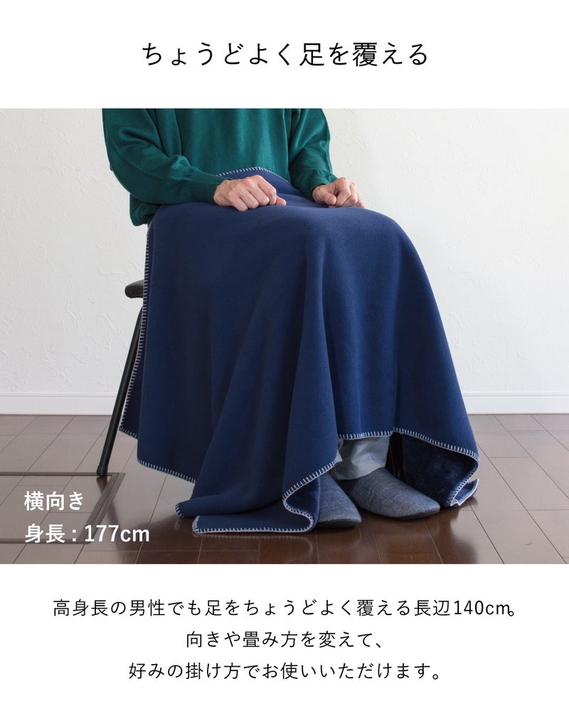 長辺140cmのMr. ブランケットのネイビーを横向きに掛け、身長177cmの男性でも座ったまま足元までちょうどよく覆える様子。