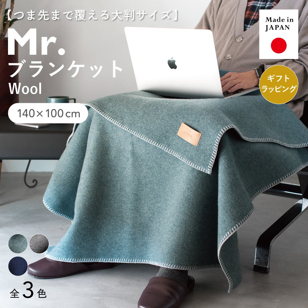 つま先まで覆える140×100cmの大判サイズのMr. ブランケット ウールのブルーグレーをひざに掛け、ノートパソコンで作業する日本製・全3色の着用イメージ。