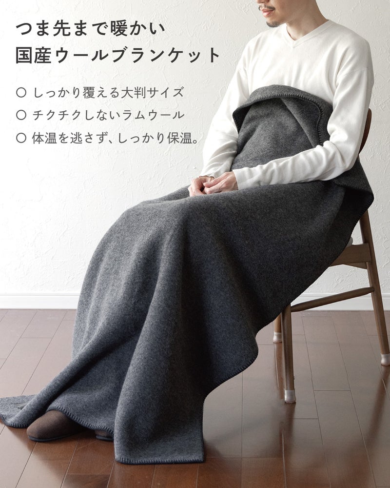 しっかり覆える大判サイズ、チクチクしないラムウール、高い保温性を備えた国産のMr. ブランケット ウールのグレーで足元まで包んで座る男性。