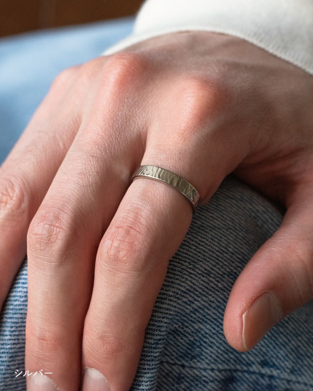 デニムの上に手を置き、シルバーの槌目リングを中指に着用している様子 