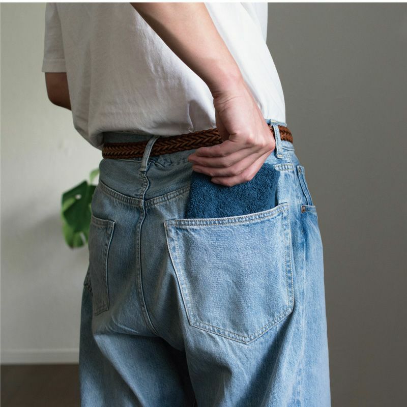 今治タオル ちょうどいいタオルハンカチ（ブルー）をジーンズのヒップポケットに収納する様子。