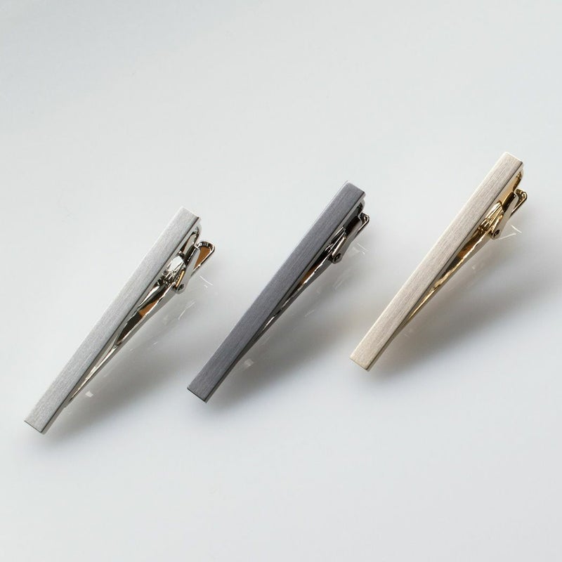 白い背景に斜めに並べられたシルバー、ブラックシルバー、ライトゴールドのシンプルなネクタイピン3本。