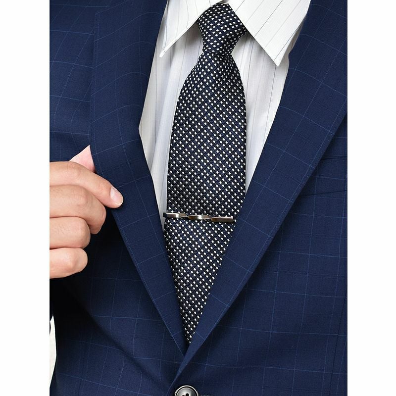 青いチェックのスーツにドット柄のネクタイとシルバーのツイストネクタイピンを着用した男性。