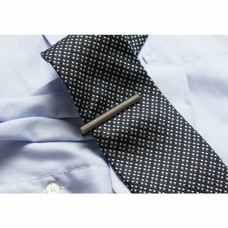 ドット柄のネイビーのネクタイに着用されたブラックシルバーのローレットネクタイピン。