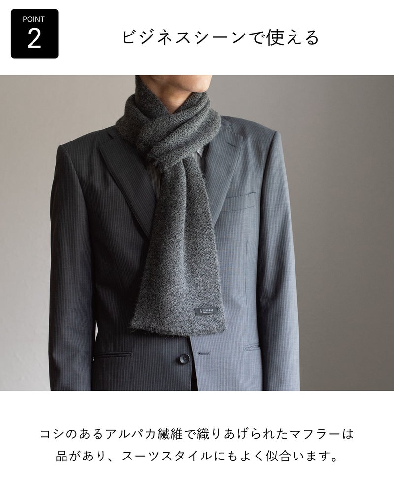 コシのあるアルパカ繊維で織りあげた品のあるグレーのアルパカ 3秒マフラーを、ストライプスーツに合わせてビジネスシーンでの使いやすさを伝える着用例。