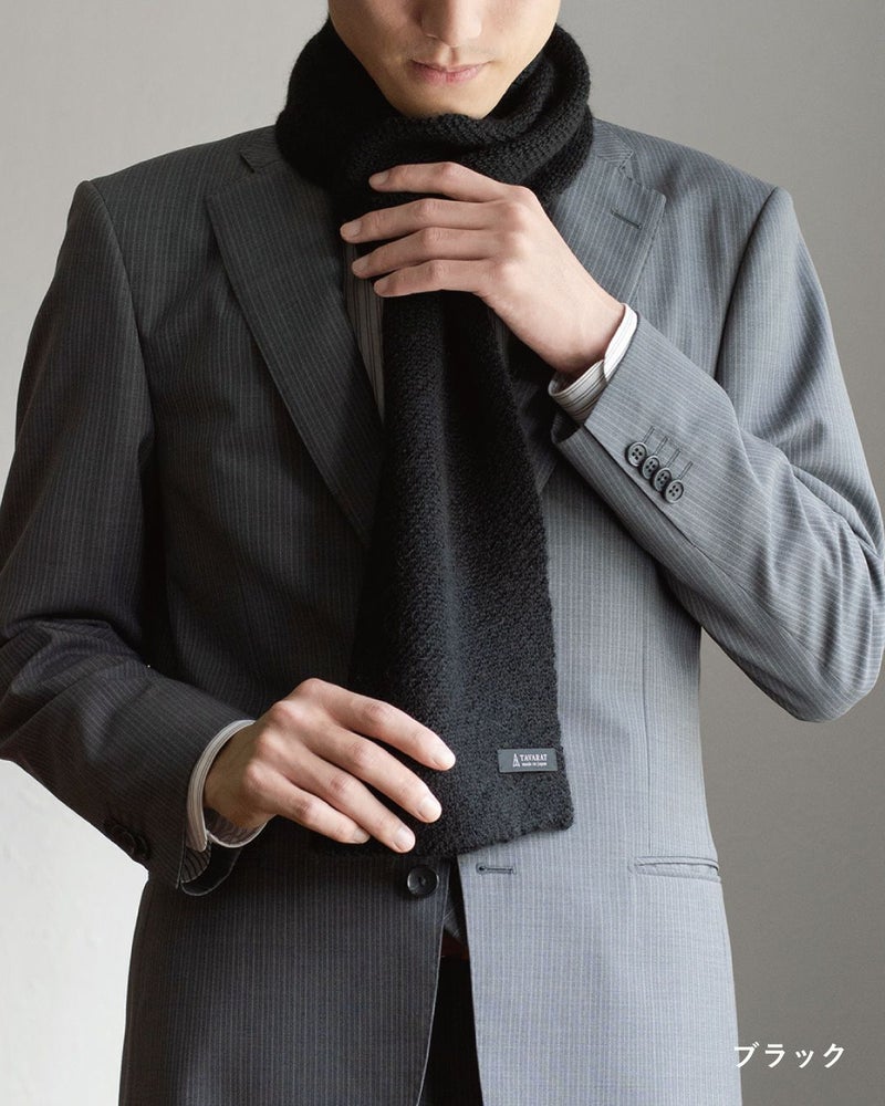 ブラック色のアルパカ100%マフラーを巻いた男性の着こなし。重厚感があり、フォーマルな装いにも合うミニマフラー。