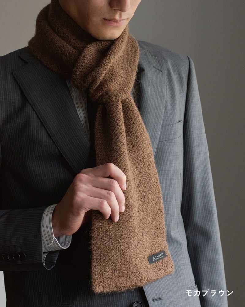 モカブラウン色のアルパカ100%マフラーを巻いた男性の着こなし。柔らかな色味でアクセントになるコンパクトマフラー。