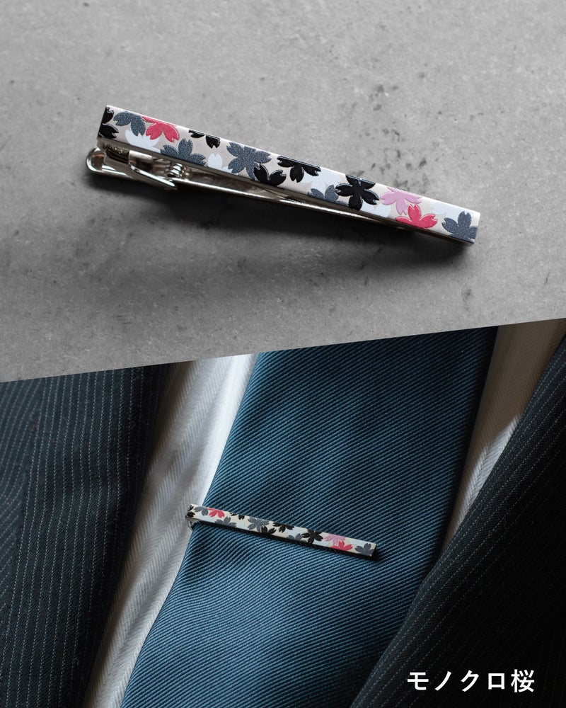 「モノクロ桜」モデル。落ち着いたグレーベースに、モノトーンの桜とアクセントの赤い花びらを散りばめたシックなネクタイピン。派手すぎず、大人の遊び心を演出するデザイン。