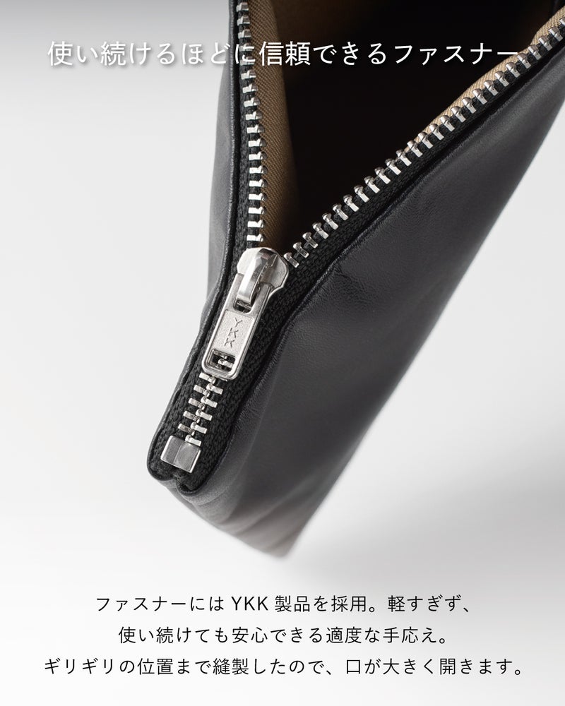 FOLMAレザーポーチのコーナー部分に装着されたYKKシルバーメタルファスナーの引き手クローズアップ。ブラックレザーに映えるシルバーの歯列となめらかな開閉感を表現。
