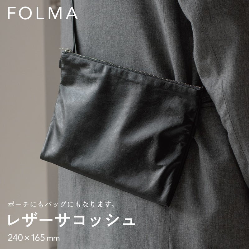 FOLMAレザーサコッシュ（240×165mm）をスーツの脇に斜めがけしたスタイリング。ポーチにもバッグにもなる2WAY仕様のブラックナッパーレザー製サコッシュ。