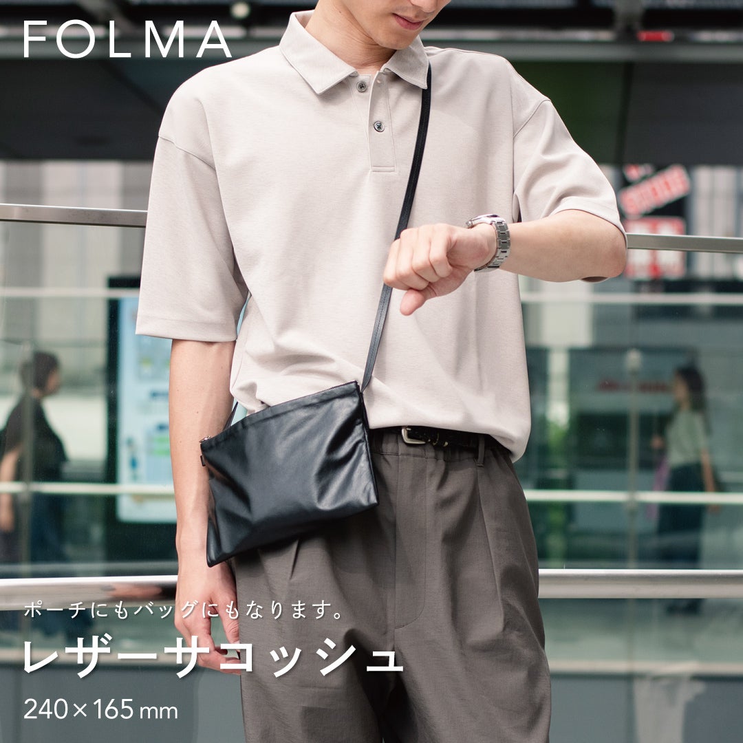 FOLMAレザーサコッシュ（240×165mm）をスーツの脇に斜めがけしたスタイリング。ポーチにもバッグにもなる2WAY仕様のブラックナッパーレザー製サコッシュ。