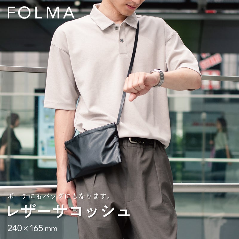 FOLMAレザーサコッシュ（240×165mm）をスーツの脇に斜めがけしたスタイリング。ポーチにもバッグにもなる2WAY仕様のブラックナッパーレザー製サコッシュ。