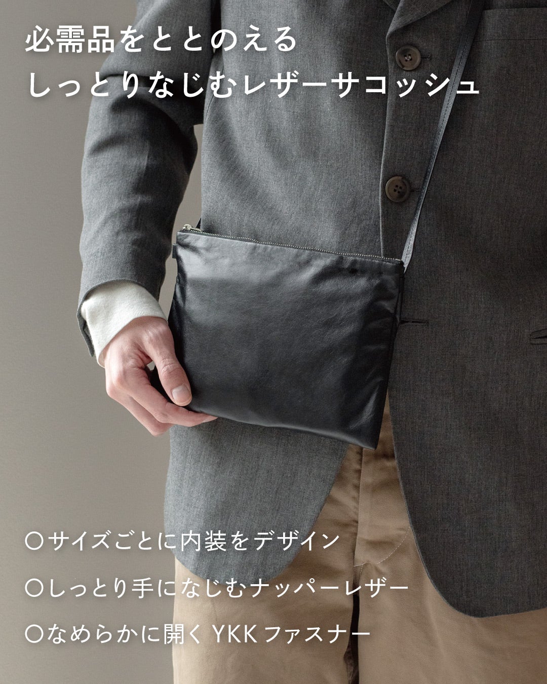 スーツ姿でFOLMAレザーサコッシュをショルダーストラップで斜めがけして手を添えるビジネスコーデ。ナッパーレザーとYKKファスナー採用で毎日の必需品をしっとりなじむ本革でまとめる。