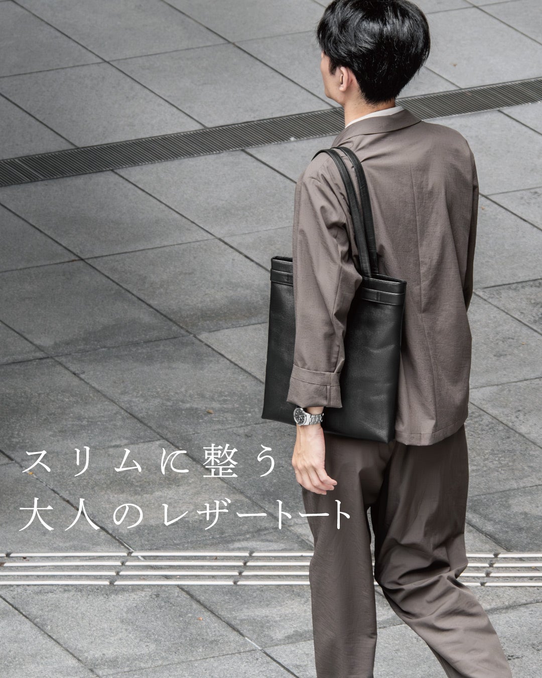 グレーのセットアップに合わせてFOLMAビジネストートを肩掛けする後ろ姿で、スリムなシルエットが大人の上品さを引き立てる着用イメージ。