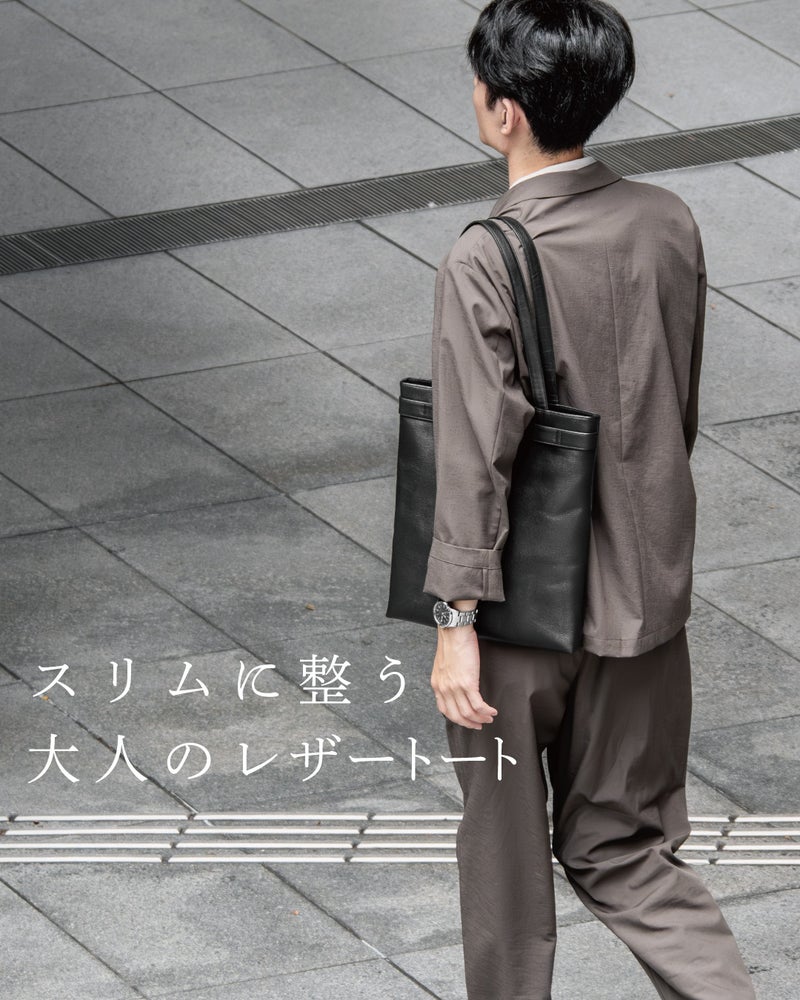 グレーのセットアップに合わせてFOLMAビジネストートを肩掛けする後ろ姿で、スリムなシルエットが大人の上品さを引き立てる着用イメージ。