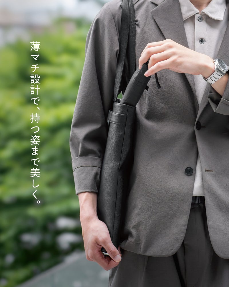 薄マチ設計のFOLMAビジネストートに折りたたみ傘を差し込むシーンで、荷物を入れても持つ姿までスマートに整うデザインを紹介。