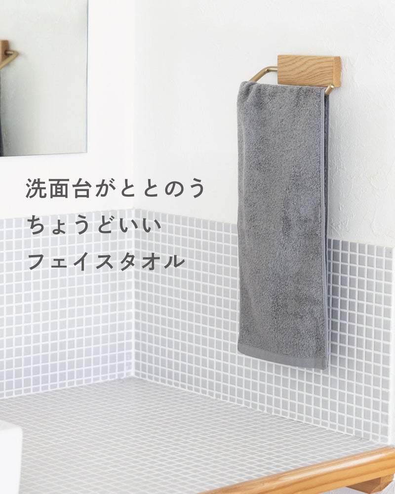 木製のタオルハンガーにグレーのちょうどいいフェイスタオルを掛け、洗面台まわりをすっきり見せるインテリア写真。