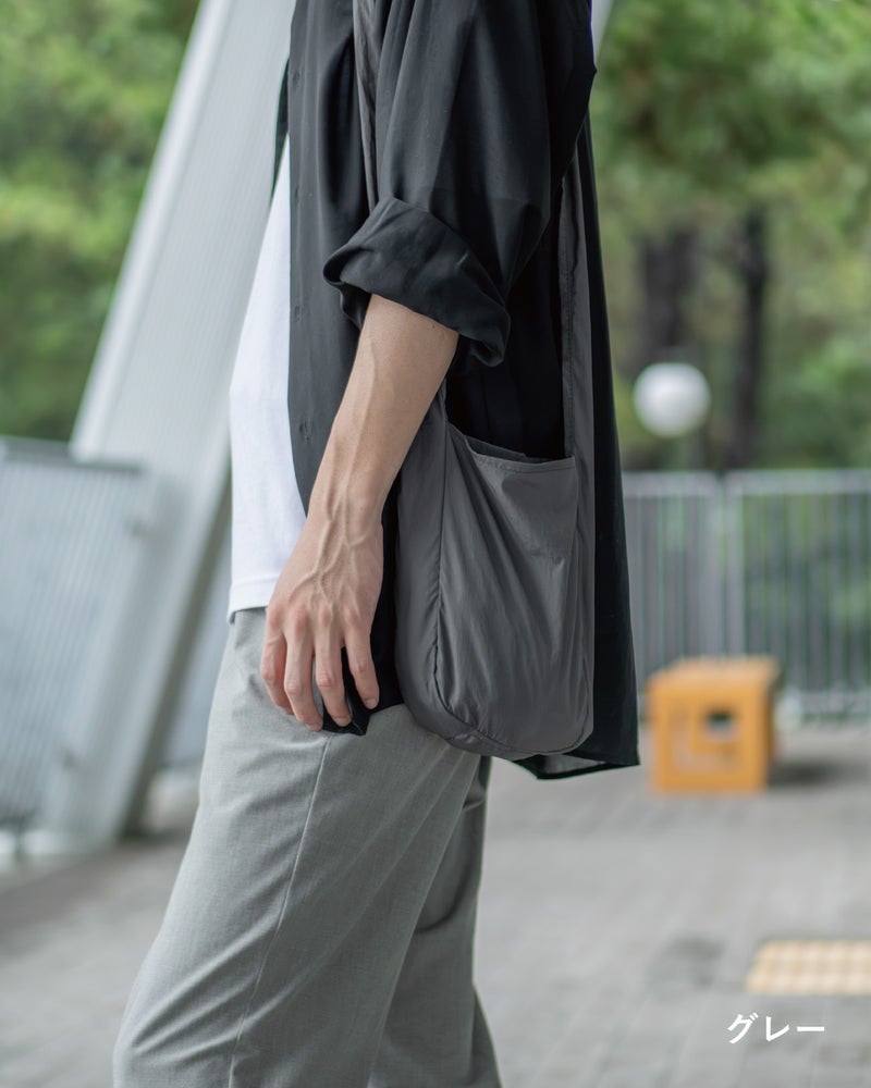 NOMAD SLING(Tav-051)のグレーを肩掛けにして街を歩く、サイドから見たコーディネート例。